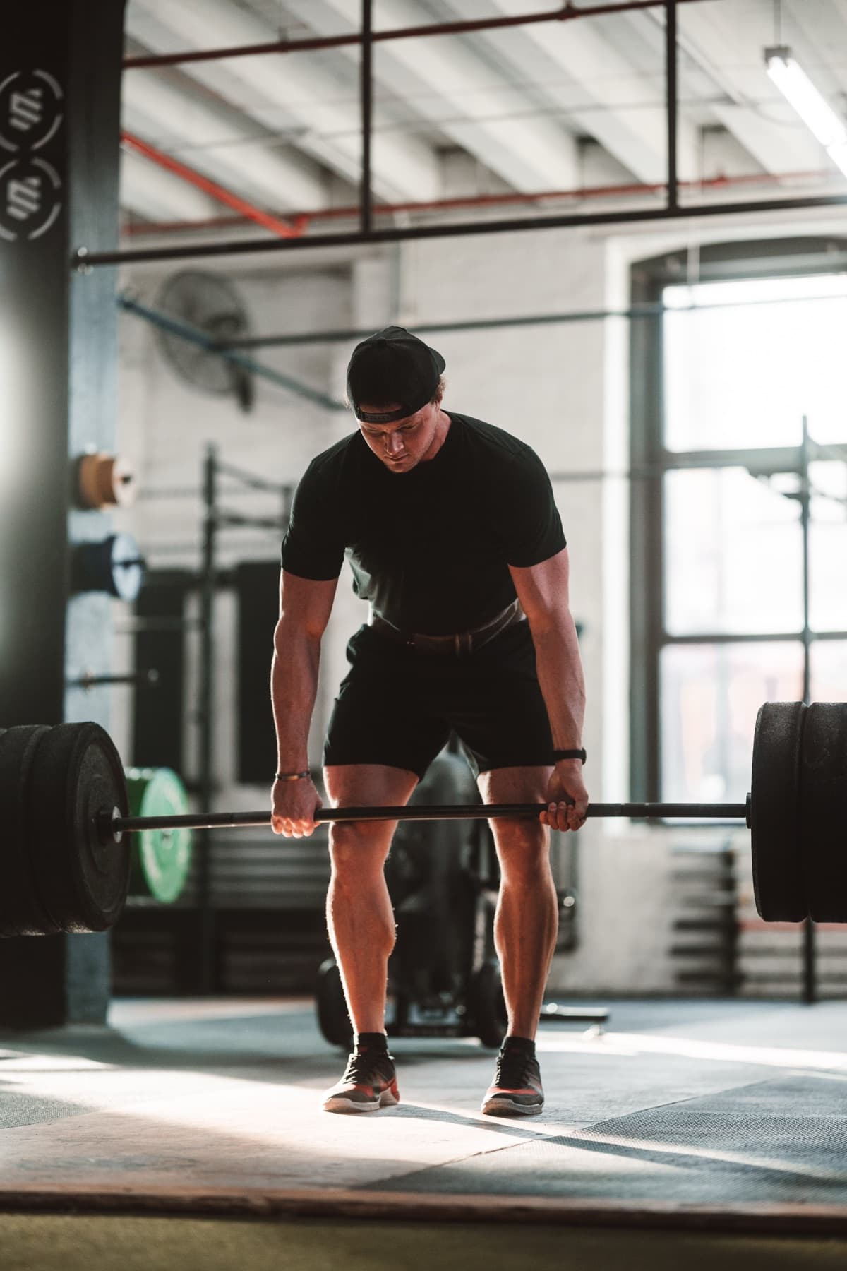 Lifter setting up for a deadlift in dramatic backlight.